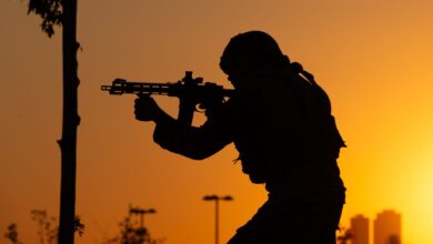 Dramatic silhouette of a soldier with a rifle against a sunrise backdrop.