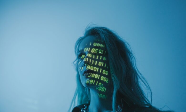 A woman with binary code lights projected on her face, symbolizing technology.