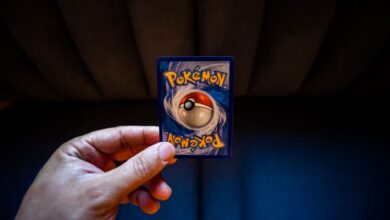 Crop unrecognizable person demonstrating collectible card dedicated to fictional creatures on dark background