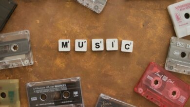 Retro cassette tapes arranged with Scrabble tiles spelling 'Music' on a brown background.