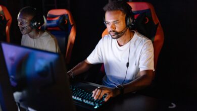 Two young men engaged in an intense esports gaming session with headsets in a dark room.