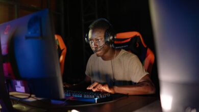 Young adult male intensely focused on computer gaming, using headset and gaming keyboard indoors.