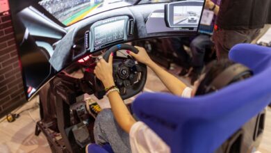Person using a realistic VR racing simulator at a gaming event, focused on the immersive experience.