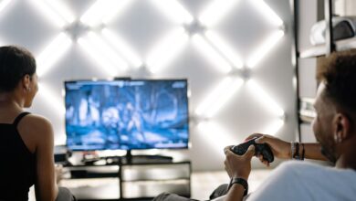 Two adults are having fun playing video games in a stylish, modern living room with LED lighting.