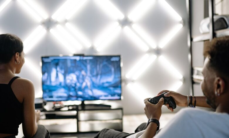 Two adults are having fun playing video games in a stylish, modern living room with LED lighting.