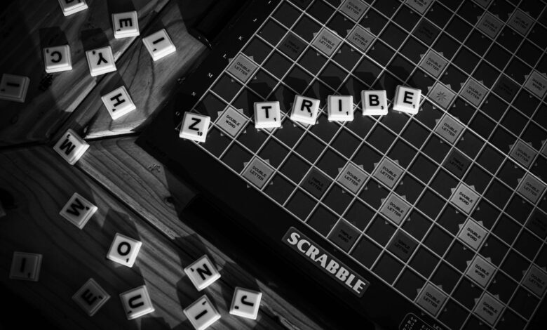 Monochrome image of a Scrabble board with letter tiles forming 'TRIBE'.