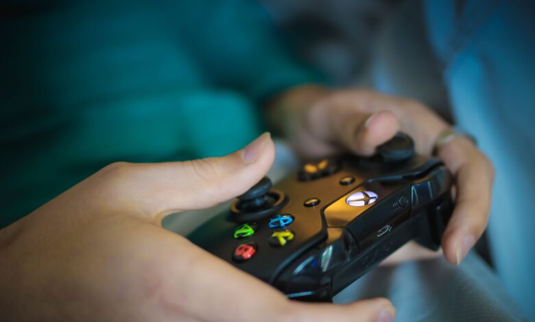 Hands gripping a modern wireless gaming controller indoors. Perfect for tech enthusiasts.