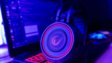 Close-up of gaming headset with neon lighting, placed next to a laptop. Perfect for tech and gaming themes.