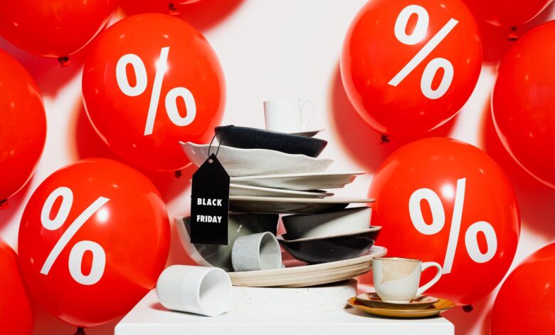 Red balloons with percentage signs surround dishes, highlighting Black Friday sales.