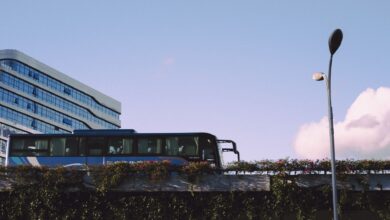 A sleek bus passes by a modern glass building under a bright blue sky.