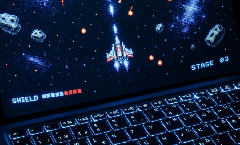 A classic arcade space shooter game displayed on a laptop with illuminated keyboard, showing retro graphics.