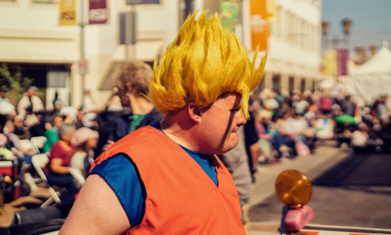 Man in Dragon Ball Z cosplay at a lively outdoor festival with a crowd in the background.