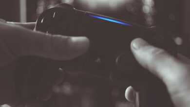 Close-up of hands gripping a gaming controller in dim light, emphasizing electronic entertainment.