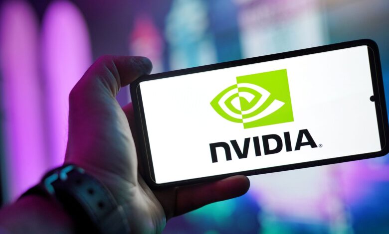 Close-up of a hand holding a smartphone showing the NVIDIA logo on screen with a blurred background.