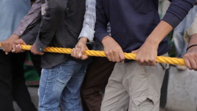 Close-up of a group participating in a tug of war, emphasizing teamwork and strength.