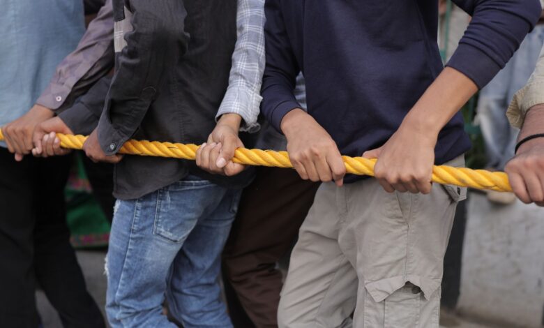 Close-up of a group participating in a tug of war, emphasizing teamwork and strength.