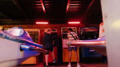 Teenagers playing classic arcade games in a dimly lit amusement arcade, embracing a retro vibe.