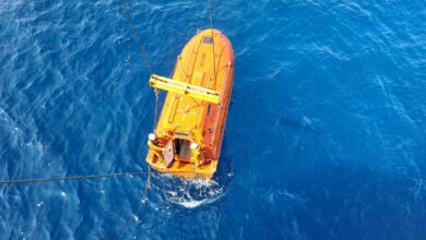 Aerial shot of an orange lifeboat in the ocean, showcasing marine transportation and safety.