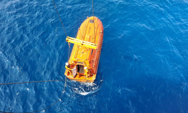 Aerial shot of an orange lifeboat in the ocean, showcasing marine transportation and safety.