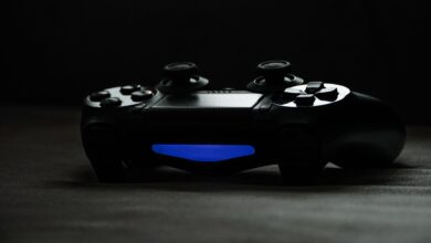 Black gaming controller with glowing blue light on a dark surface, perfect for tech-themed projects.