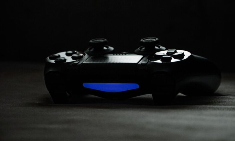 Black gaming controller with glowing blue light on a dark surface, perfect for tech-themed projects.