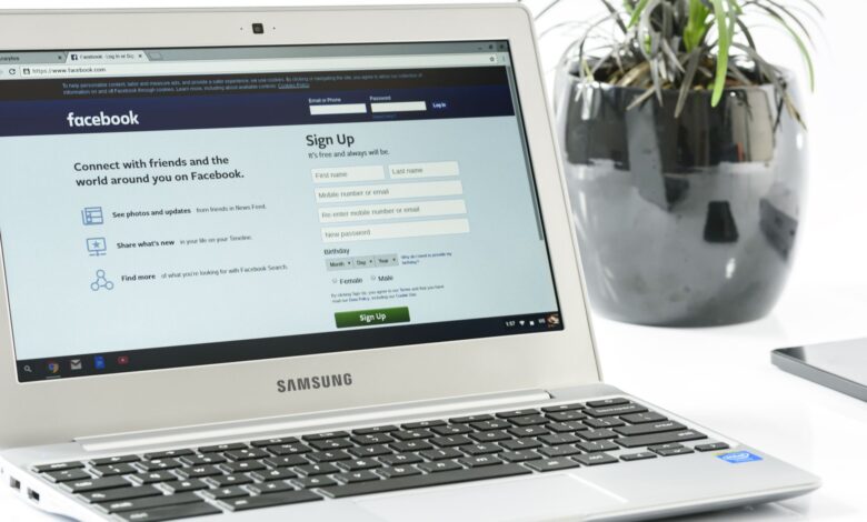 Open Samsung laptop showing Facebook sign-up page next to a potted plant. Ideal for technology themes.