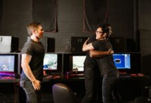 Young men celebrate a gaming win together in an eSport cyber cafe, exuding happiness and camaraderie.