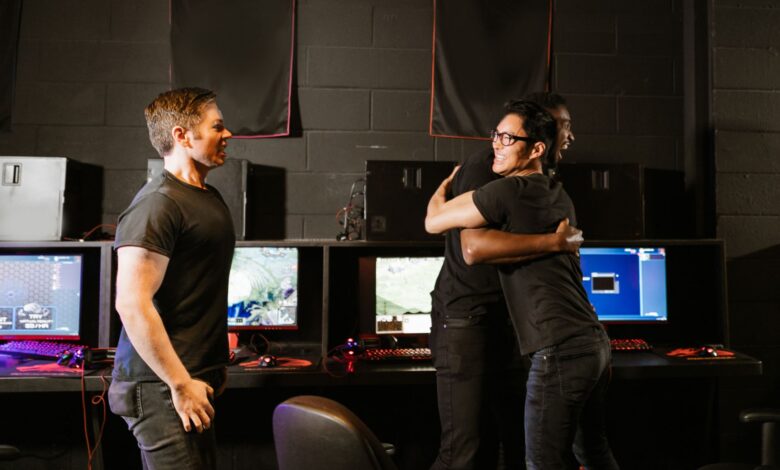 Young men celebrate a gaming win together in an eSport cyber cafe, exuding happiness and camaraderie.