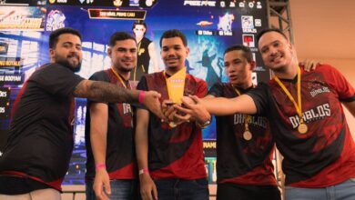 A group of gamers celebrating their victory at an e-sports event holding a trophy.