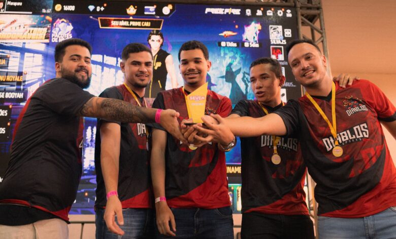 A group of gamers celebrating their victory at an e-sports event holding a trophy.