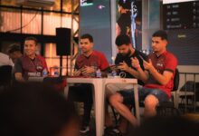 A group of e-sports players participating in a gaming event, focused on smartphone gameplay.