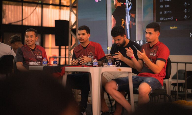 A group of e-sports players participating in a gaming event, focused on smartphone gameplay.