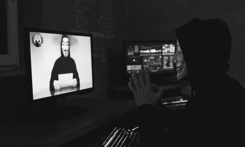 Monochrome image of a masked hacker on a video call, showcasing cyber security themes.