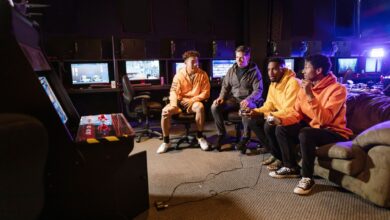 A group of young men having fun gaming together indoors, using controllers and arcade machines.