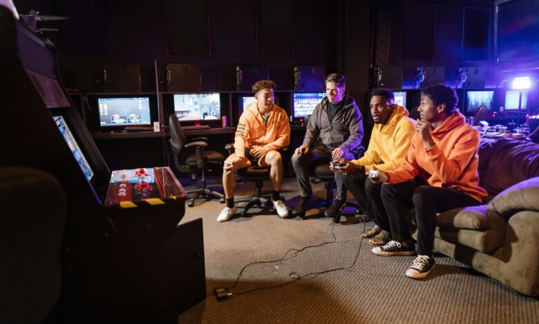 A group of young men having fun gaming together indoors, using controllers and arcade machines.