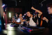 Excited gamers celebrating a win in a competitive gaming tournament with headphones.