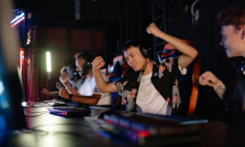 Excited gamers celebrating a win in a competitive gaming tournament with headphones.