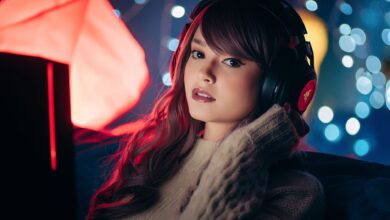 A woman wearing headphones poses indoors with a cozy setting, ideal for gaming themes.