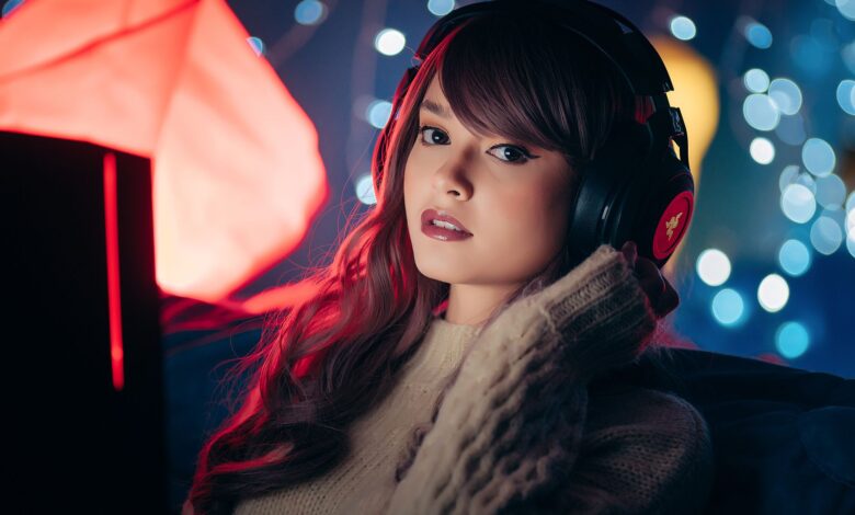 A woman wearing headphones poses indoors with a cozy setting, ideal for gaming themes.