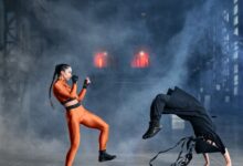 Two cosplayers in martial arts poses amidst smoke, embodying game characters in action.