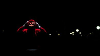 A spooky figure wearing a glowing LED mask in the darkness, perfect for Halloween themes.