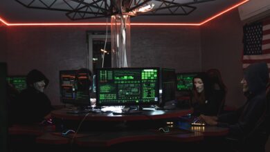Team of hackers with Guy Fawkes masks coding in a dark room with computers.