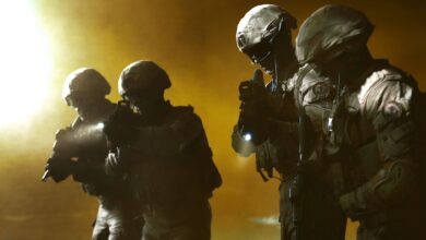 Four soldiers in tactical gear advancing in a smoky battlefield setting.