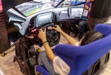 Person using a realistic VR racing simulator at a gaming event, focused on the immersive experience.