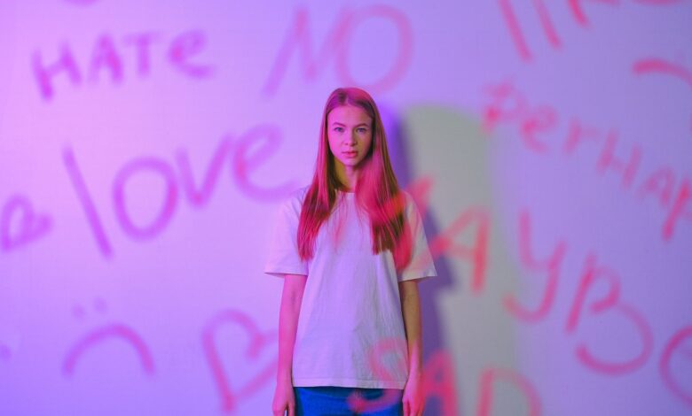 Expressive studio portrait of a teenager with graffiti, capturing emotion and mood with a pink hue.