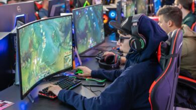 Gamers in an esports tournament playing on high-end gaming setups with monitors, keyboards, and headphones.