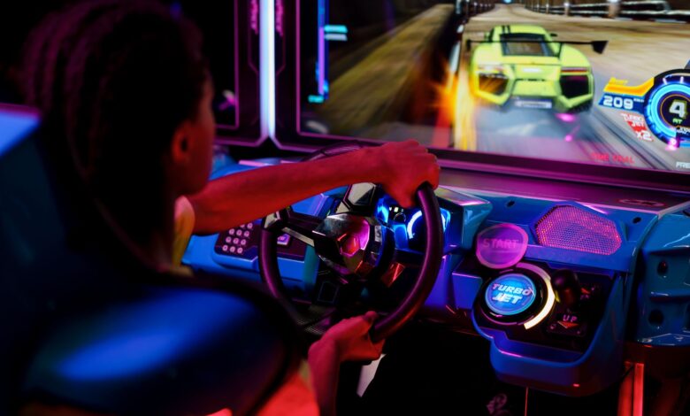 A person playing an immersive arcade racing game with vibrant lights.