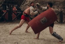 Two gladiators engaged in intense combat in a historical arena setting.