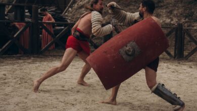 Two gladiators engaged in intense combat in a historical arena setting.