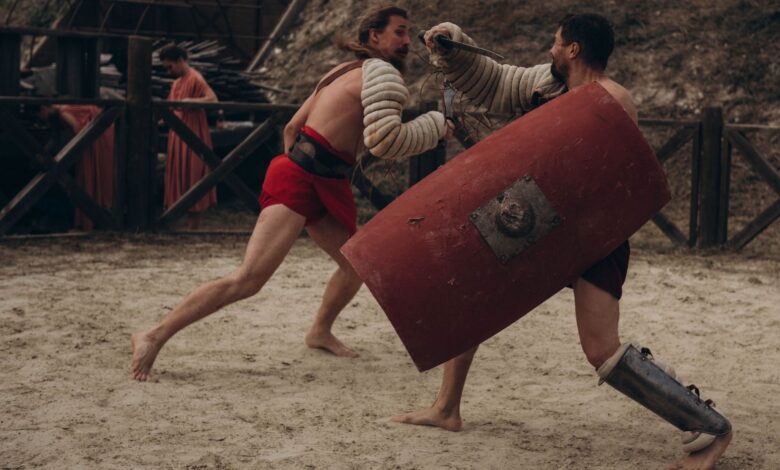 Two gladiators engaged in intense combat in a historical arena setting.
